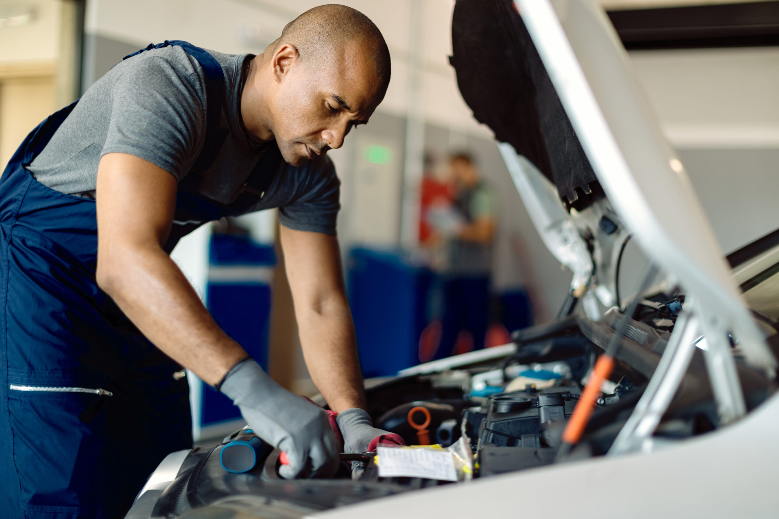 mecanico afroamericano reparando motor coche taller scaled